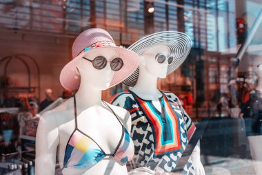 Moda mağazası ve butiğin vitrininde mayo ve şapka giymiş bir manken. Tatil ve tatil kıyafetleri