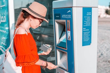 28 November 2019, UAE, Dubai: Tourist girl top up her Nol transport card in Atm terminal near bus stop
