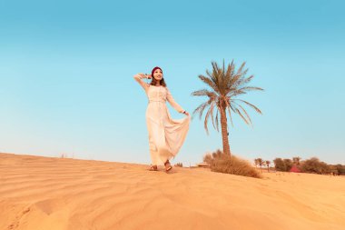Happy asian woman in turban travels in Sahara desert. Adventure and life experience concept