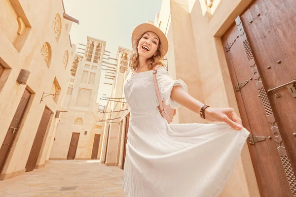 Šťastná asijská dívka v bílých šatech procházející se úzkými uličkami starého města někde na Blízkém východě. Cestovní destinace a koncepce cestovního ruchu — Stock fotografie
