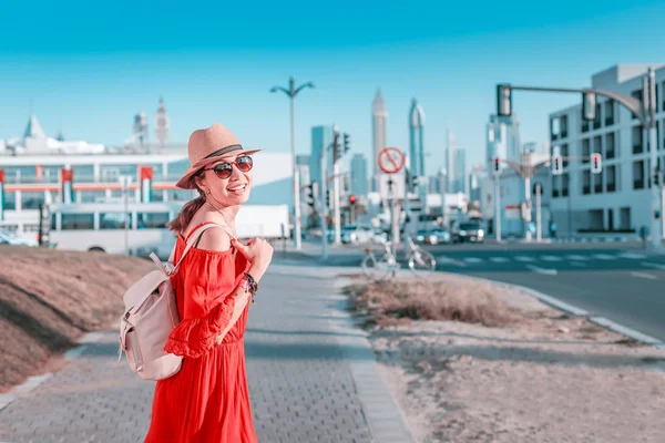 Туристическая девушка с рюкзаком прогулки по тротуару рядом с оживленной улице в Дубае — стоковое фото