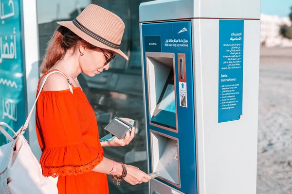 28 November 2019, UAE, Dubai: Tourist girl top up her Nol transport card in Atm terminal near bus stop — Stok fotoğraf