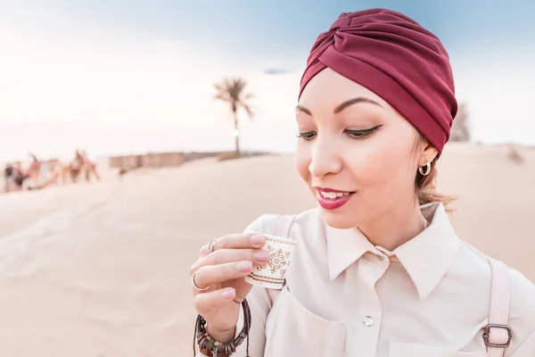 Мусульманка с тюрбаном дегустирует арабский кофе во время тура и экскурсии по средней восточной пустыне — стоковое фото