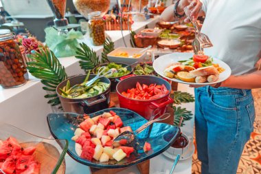 Woman choosing food in open buffet at breakfast in hotel