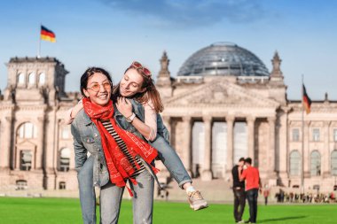 İki kız arkadaş, öğrenciler ya da turistler Berlin 'deki Bundestag binasının yakınındaki çimlerde iyi vakit geçiriyorlar. Covid-19 'un salgınından ve tecridinden sonra Almanya