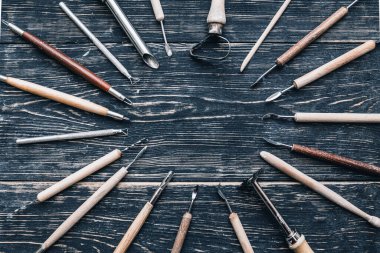 Çömlekçilik için işlenmemiş kil oymak ve çalışmak için çeşitli araçların düz üst görünümü. Hobi kavramı ve evde ve atölyede yaratıcı bir eğlence.