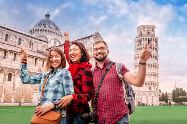 Eğlenceli ve çeşitli bir grup genç turist Pisa 'daki ünlü meyilli kuleye karşı poz veriyor. Karantina ve tecrit kavramının iptali sonrasında İtalya 'da turizm