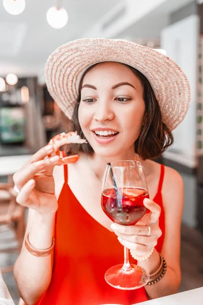 Komik Asyalı kız taze karides yiyor ve sangria içiyor. Akdeniz mutfağı ve lezzetli deniz ürünleri kavramı