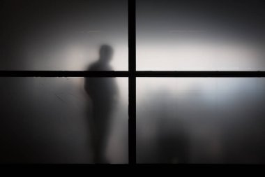 Keçeleşmiş cam arkasındaki adam silüeti