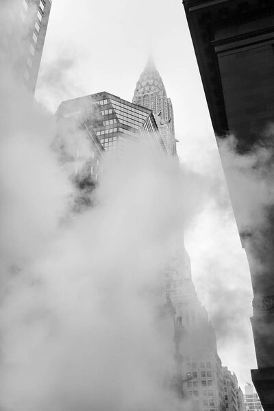 NEW YORK, USA - May 03, 2016: Empire State Building. Manhattan street scene. Cloud of vapor from the subway on the streets of Manhattan in NYC. Typical view of Manhattan