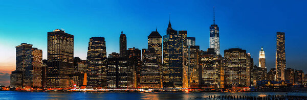 Manhattan at night. New York City skyline panorama with lights and reflections.