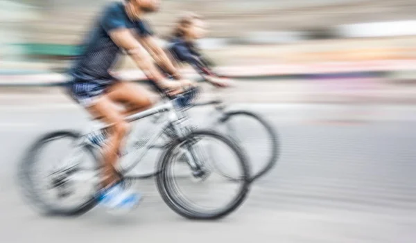Young man and woman riding bicycles on a city street — Stock Photo, Image