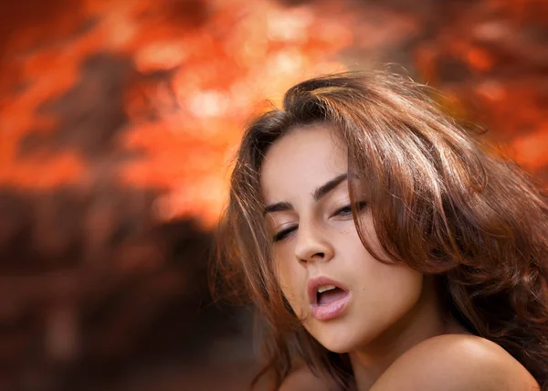 Emotional young woman against red blured nature background — Stock Photo, Image