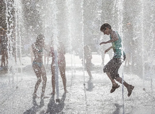 Gelukkige kinderen spelen in een waterfontein in een hete dag — Stockfoto