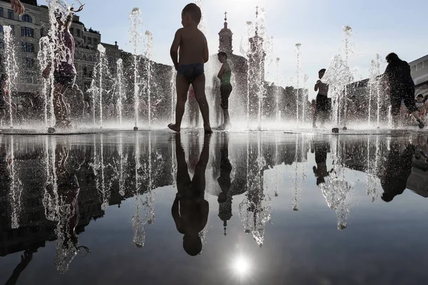 Crianças felizes brincando em uma fonte de água em um dia quente — Fotografia de Stock
