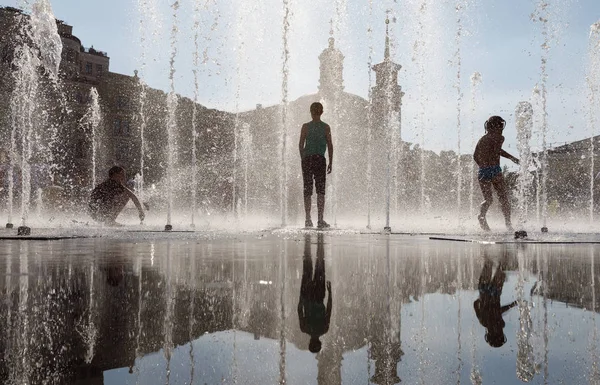 Enfants heureux jouant dans une fontaine d'eau dans une journée chaude — Photo