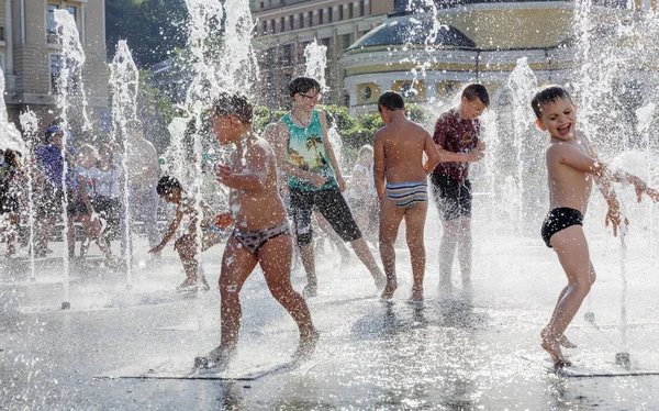 Crianças felizes brincando em uma fonte de água em um dia quente — Fotografia de Stock