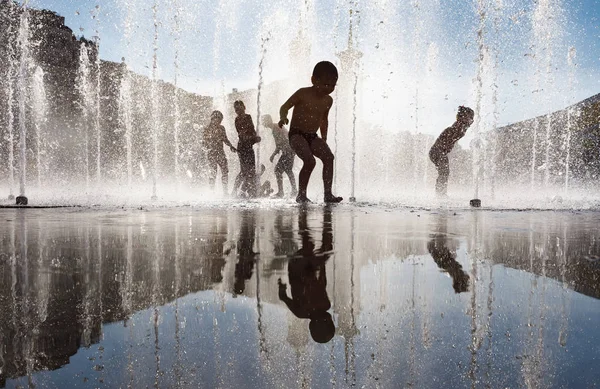 Happy children playing in a water fountain in a hot day — Stock Photo, Image