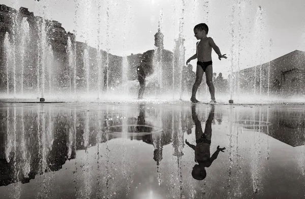 Enfants heureux jouant dans une fontaine d'eau dans une journée chaude — Photo