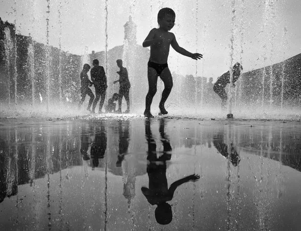 Niños felices jugando en una fuente de agua en un día caluroso —  Fotos de Stock