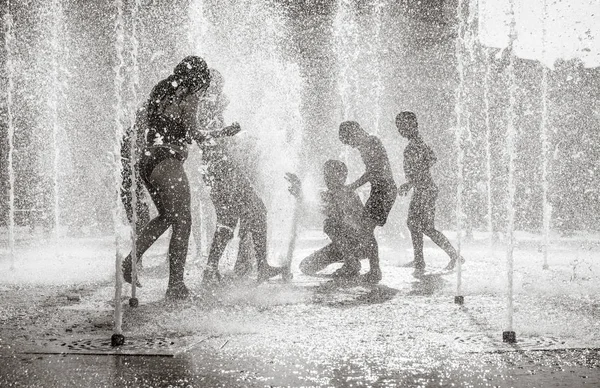 Happy children playing in a water fountain in a hot day — Stock Photo, Image