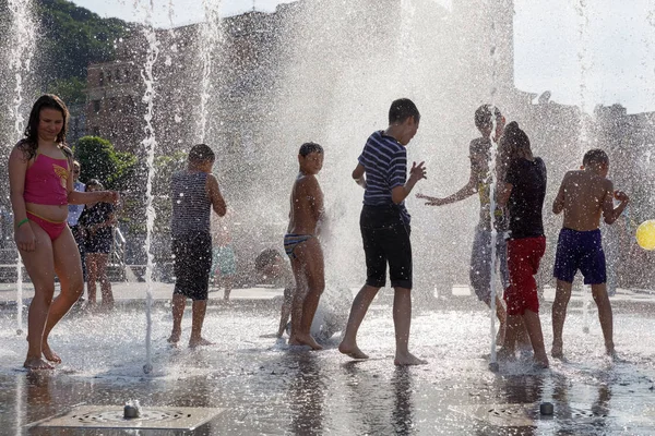 Glada barn som leker i en fontän i en varm dag — Stockfoto