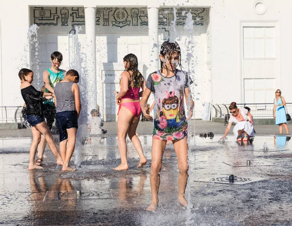 Crianças felizes brincando em uma fonte de água em um dia quente — Fotografia de Stock