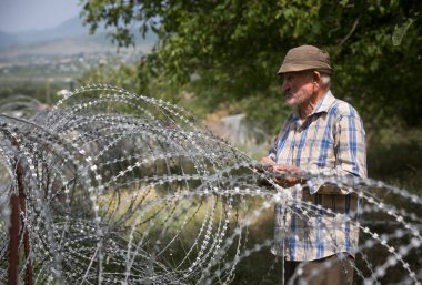 Yaşlı adam dikenli tel yakınındaki yerel stand