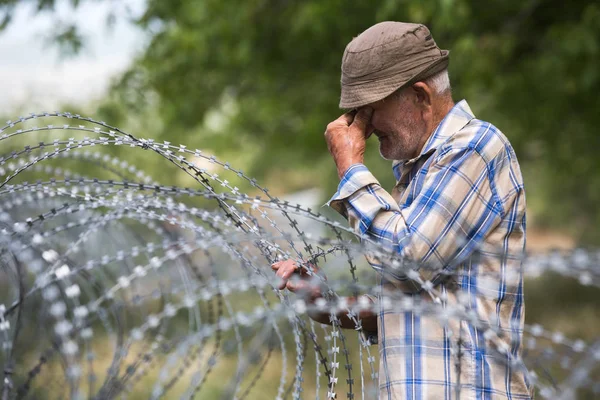 Viejo en el puesto local cerca de alambre de púas —  Fotos de Stock