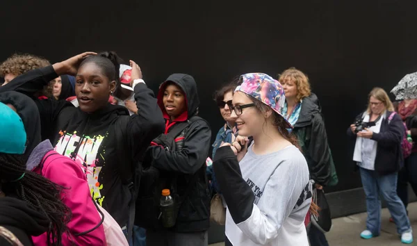 Group of young people against black wall — Stock Photo, Image