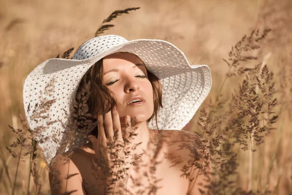 Een jonge vrouw in een witte hoed geniet van de zon — Stockfoto