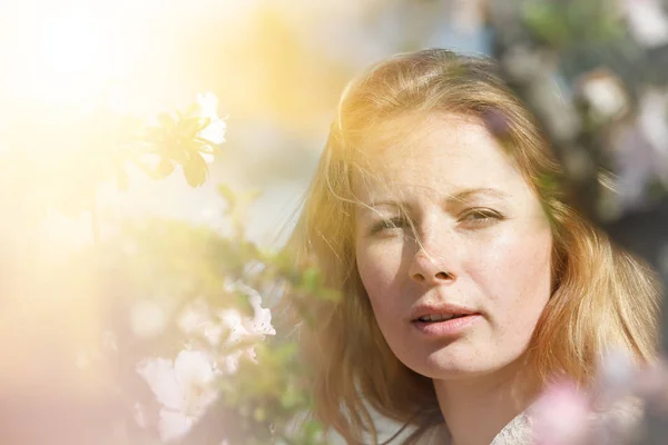 Blond meisje tussen de bloemen — Stockfoto