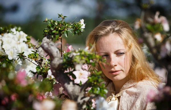 Blond meisje tussen de bloemen — Stockfoto