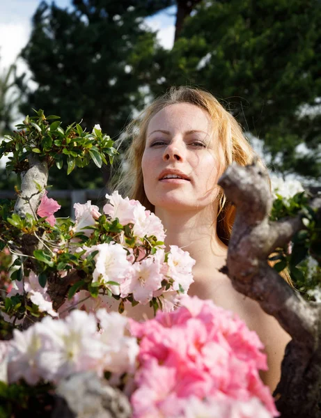 Blond meisje tussen de bloemen — Stockfoto