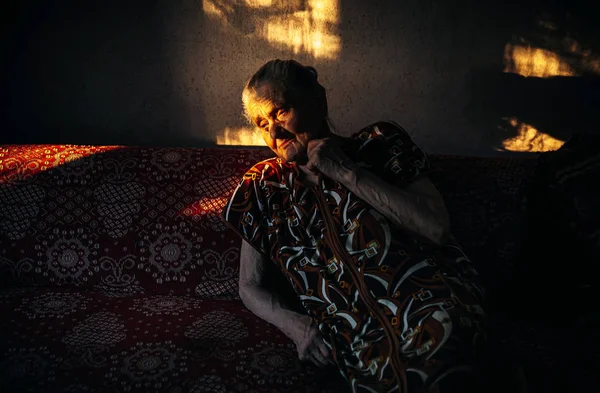 Mujer arrugada muy vieja y cansada sentada en un sofá — Foto de Stock