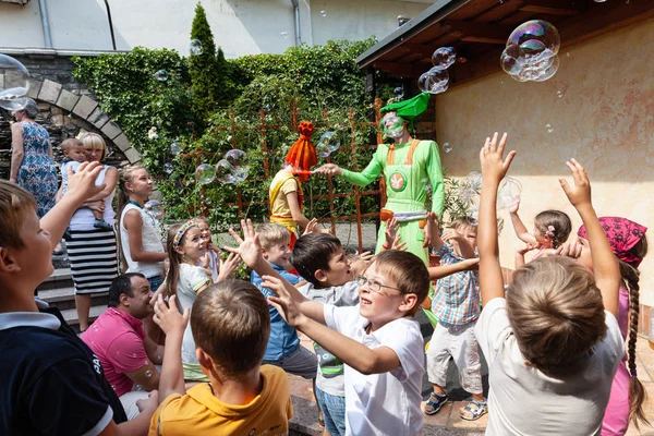 Clowns show soap bubbles to children — Stock Photo, Image