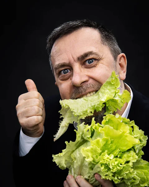 Uomo che tiene e mangia lattuga — Foto Stock