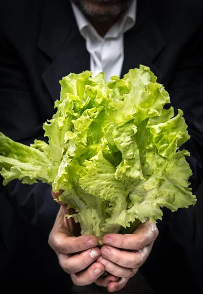 Hombre sosteniendo y comiendo lechuga — Foto de Stock