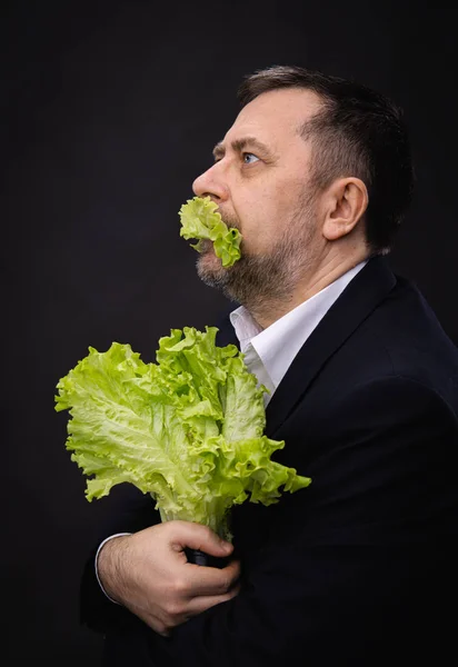 Hombre sosteniendo y comiendo lechuga — Foto de Stock