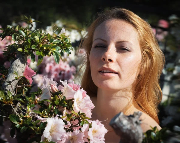 Junge Frau inmitten der Azaleen-Blüten — Stockfoto