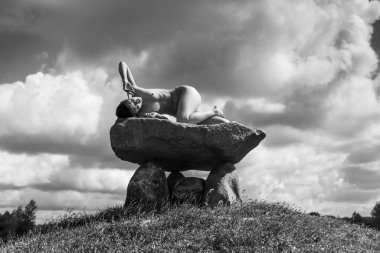 Tepenin tepesinde çıplak bir kadın poz veriyor.