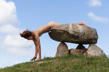 Tepenin tepesinde çıplak bir kadın poz veriyor.