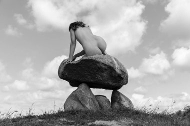 Tepenin tepesinde çıplak bir kadın poz veriyor.