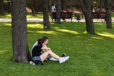 Kyiv, Ukrayna - Haziran. 06, 2019: Volodymyrska Hill veya Kyiv 'deki Saint Volodymyr Hill. Gençler parkta çimlerin üzerinde dinleniyorlar..