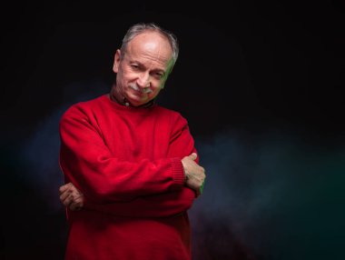 Kırmızı kazaklı yaşlı bir adamın stüdyo portresi.