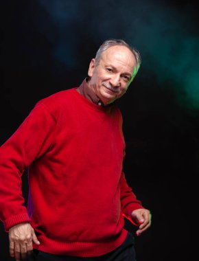 Kırmızı kazaklı yaşlı bir adamın stüdyo portresi.