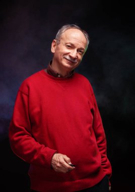 Kırmızı kazaklı yaşlı bir adamın stüdyo portresi.