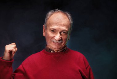 Kırmızı kazaklı yaşlı bir adamın stüdyo portresi.