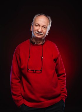 Gözlüklü, kırmızı kazaklı yaşlı bir adamın stüdyo portresi.