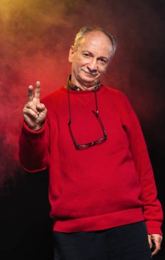 Gözlüklü, kırmızı kazaklı yaşlı bir adamın stüdyo portresi.